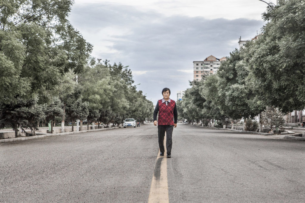 Aux portes du desert de Gobi, le Fort de Jiayuguan datant de la dynastie Ming, est surtout connu des touristes chinois pour marquer la fin de la Grande Muraille.
A partir de 1958, la petite ville de Jiayuguan située un peu plus au sud entre dans une ère nouvelle quand l’industriel JISCO (Jiuquan Steel and Iron Group) s’y installe pour devenir aujourd’hui le premier producteur de fer et d’acier du nord ouest de la Chine.
Principal employeur et moteur économique de cette ville et de sa préfecture de 120 000 habitants , l'acierie et ses activités dérivées sont omniprésentes dans le paysage urbain: ouvriers à vélo électrique et en bleu de travail, habitants des cités faisant leurs exercices physiques devant les fumées des cheminées d'usine, bâtiments industriels érigés tels des monuments comme les statuaires glorifiant l expansion économique et touristique récente de la ville….
Par ailleurs, malgré les pénuries d'eau dues a son importante utilisation industrielle, les activités agricoles sont bien présentes et c'est principalement sur les 2 grands marches de Jiayuguan que les habitants viennent se ravitailler.